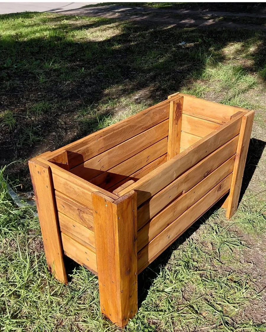 Jardinera rectangular de listones de madera barnizada sobre el pasto
