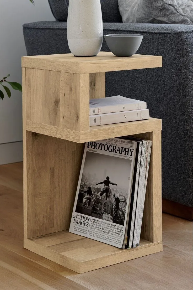 Mesa auxiliar de madera clara de dos niveles con revistas y una planta
