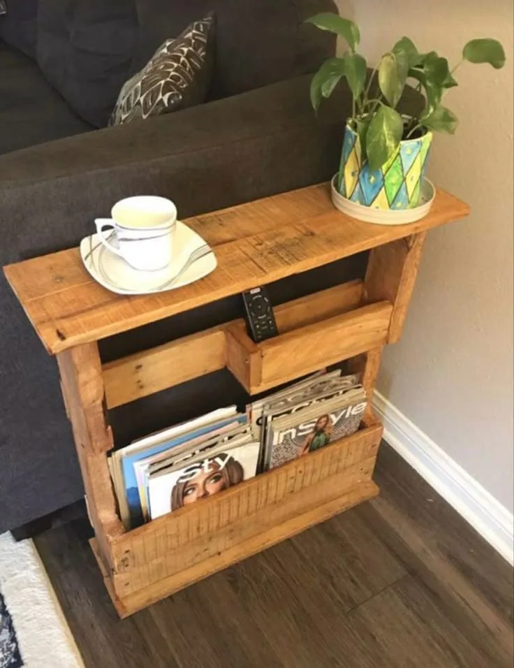 Mesa auxiliar de madera con un revistero lateral, apoyada contra un sillón